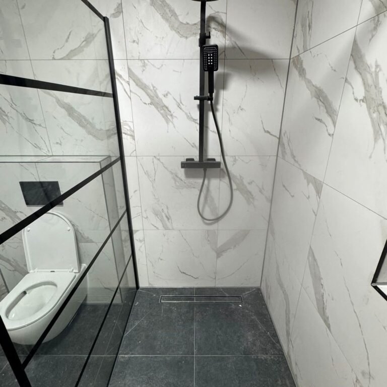 Inloopdouche met marmerlook tegels en zwart stalen raam naast een hangend toilet