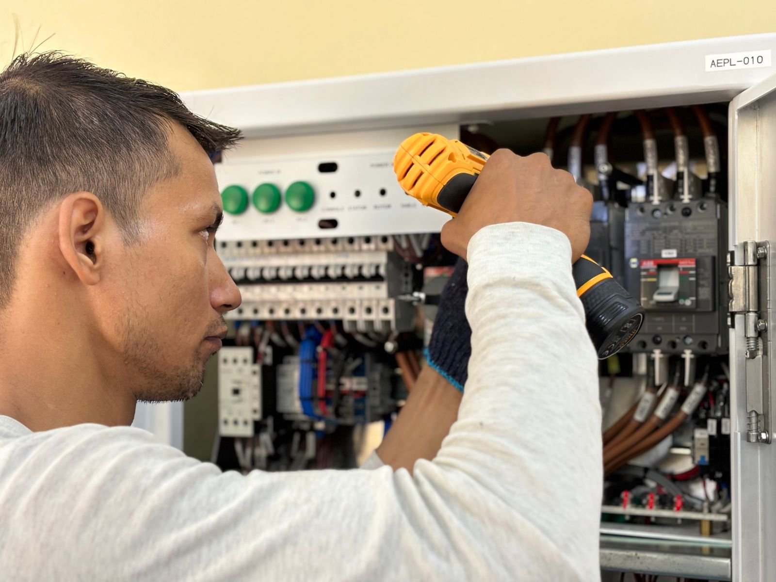 Elektricien werkt met een boormachine aan een groepenkast