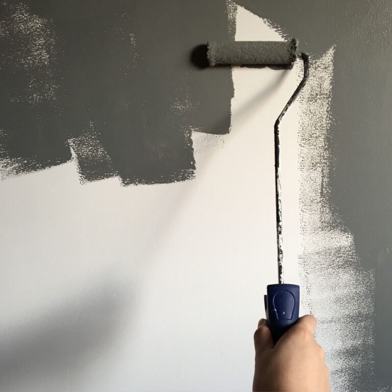 Schilder rolt een muur in een lichtgrijze kleur