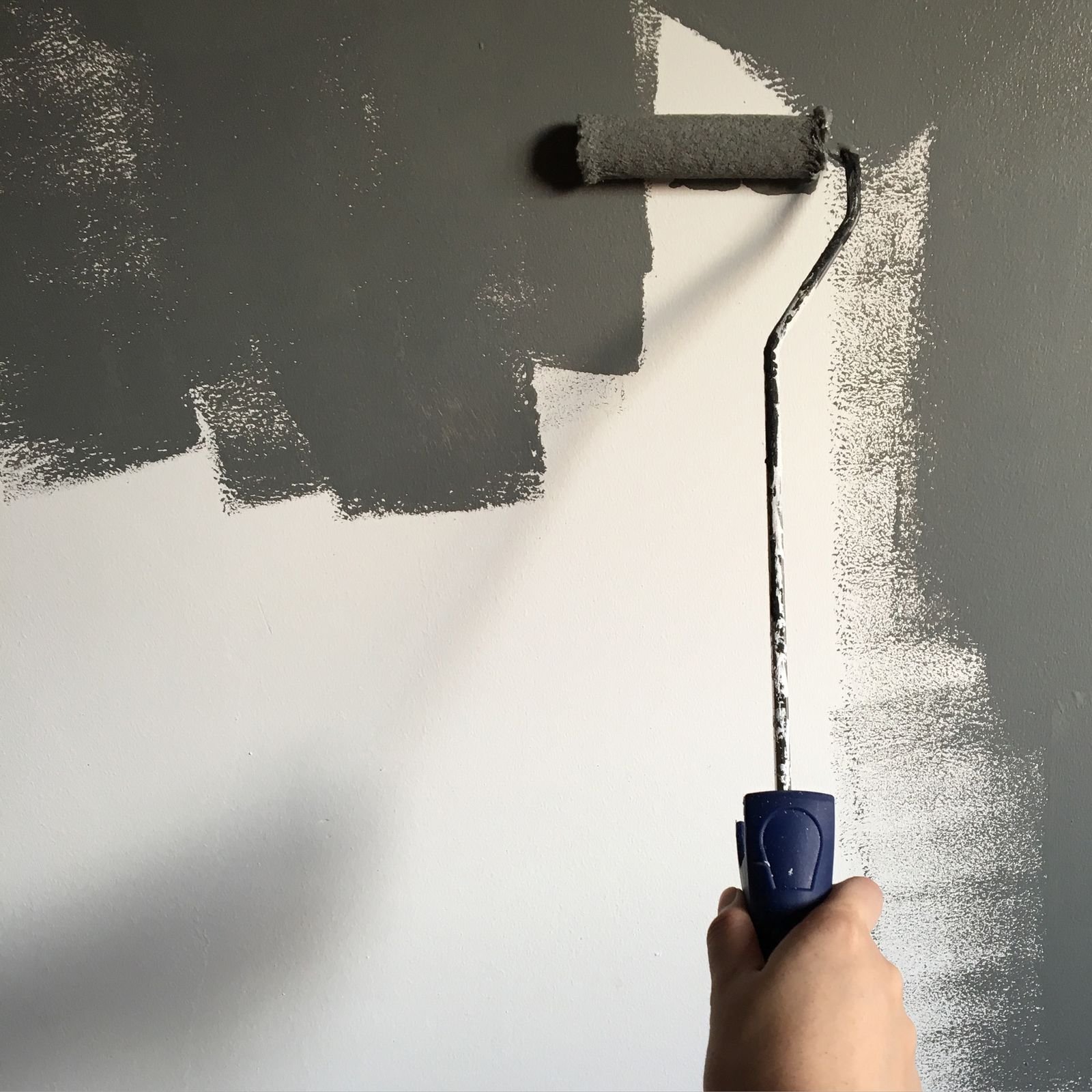 Schilder rolt een muur in een lichtgrijze kleur